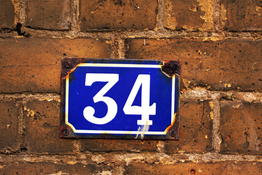Number 34 street sign plate on a brick wall