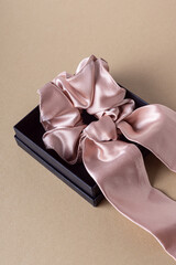 Silk hair clip in black box on beige background. Pink scrunchy. Elastic band for hair