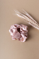 Silk hair clip and ears of wheat on beige background. Pink scrunchy.  Comfortable elastic band for hair