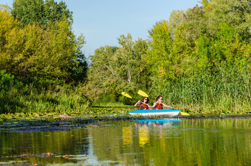 Naklejka premium Family kayaking, mother and child paddling in kayak on river canoe tour, active autumn weekend and vacation, sport and fitness concept