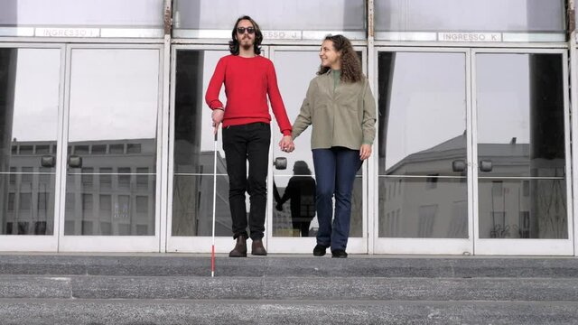 love, empathy -woman helps her boyfriend with a disability to go down the stairs