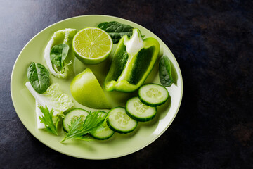 Organic green vegetables and fruits on a dark background. Green diet food on a plate. Healthy food. Top view. Copy space