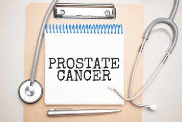 White notepad with the words prostate cancer and a stethoscope on a blue backgroundd. Medical...