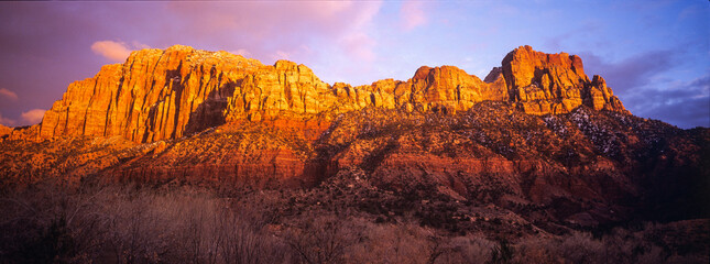 Mountain west of Zion NP lit orange by sunset with clouds
