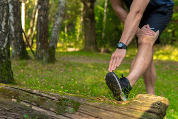 A young enduring athletic athlete is doing stretching in the forest outdoors, around the forest, oak trees.run forest, fitness outdoor endurance jog, woods man. Autumn leisure feet stretches