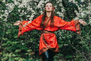 Young girl in traditional kimano in a blooming garden with samurai japanese sword katana in image...