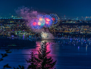 Beautiful shot of bright colorful exploding fireworks in a city over water