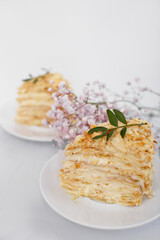 Piece of Napoleon cake on a white saucer isolated on a white background. Cake of puff pastry with sour cream. Copy space.