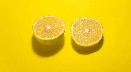 two lemon cut into slices on yellow background