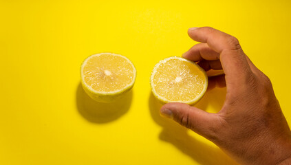two lemon cut into slices on yellow background holding it by the hand