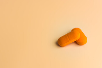 Two large orange pills on a gentle orange background.