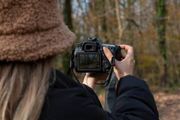 A photographer girl taking nature in autumn. She has brown hat. Hobby concept. Unrecognizable person.
