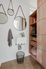 Minimalist washroom sink with round mirrors and lots of storage for towels 