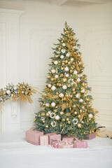 Large Christmas tree in gold and pastel pink colors in classic wite room