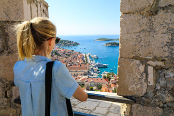 Fototapeta na wymiar Blonde woman tourist enjoying view of Hvar harbor from Spanish fort