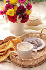 Cup of hot coffee, delicious cookies and beautiful bouquet on wooden table