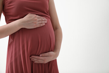 Young pregnant woman on light background, closeup. Space for text