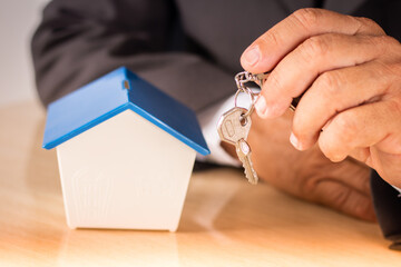 Business man holding key with small house on table. housing concept
