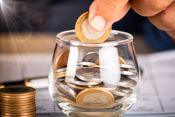 Businessman holding coins and putting into glass pot. Saving concept for financial accounting