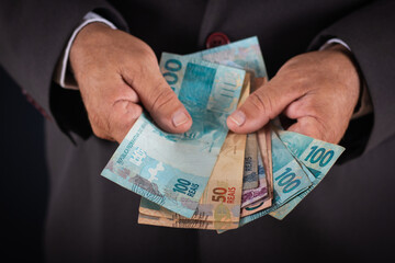 Business man showing you brazilian money. business concept