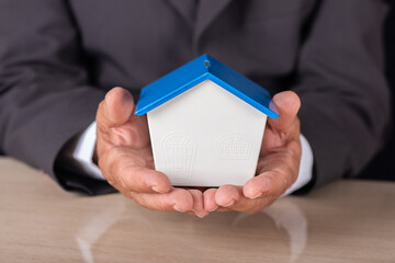 Business man holding small house in his hand. housing concept