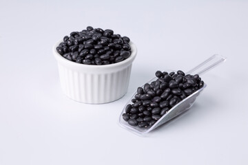 black bean in white bowl and plastic spoon on white background studio shot
