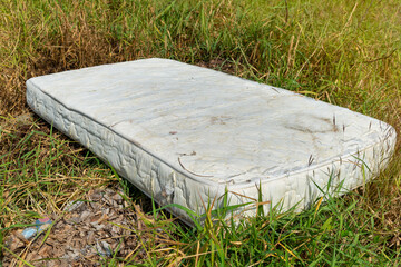 Old mattress on the grass,  Forgotten, rusty, dirty torn old Mattress, Old discarded mattress on the street. Homelessness or poverty