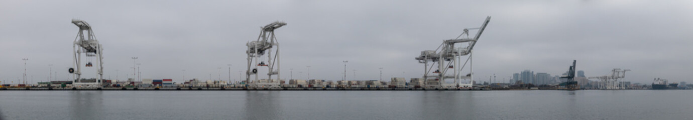 Fototapeta na wymiar Inactive because of supply chain issues, cranes are quiet on a foggy day at the port of Oakland with Oakland skyline in background