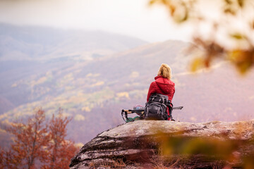 Hiker girl taking a rest on a rock in the mountains. Windy day. Travel and healthy lifestyle...