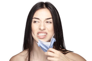 Angry girl pulling away medical face mask. Portrait against white background.