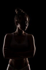 Studio portrait of a fit girl. Half silhouette side lit fitness model.