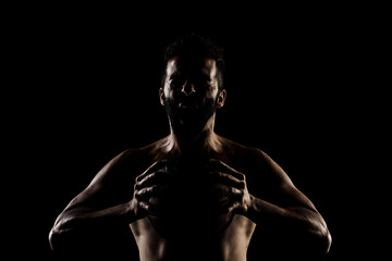 Fototapeta na wymiar Basketball player holding a ball against black background. Side lit muscular Caucasian man silhouette