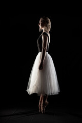 ballerina with a white dress and black top posing on black background © Nikola Spasenoski