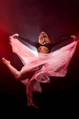 ballerina with a white dress and black top posing on red smoke background © Nikola Spasenoski