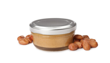 Jar with delicious peanut butter and nuts on white background