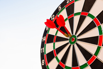 Dart arrow hitting to center on bullseye (bull's-eye) dartboard is the target of purpose challenge business at sunset, expert marketing strategy target, objective financial and goal success