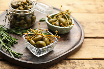 Delicious pickled capers and rosemary on wooden table