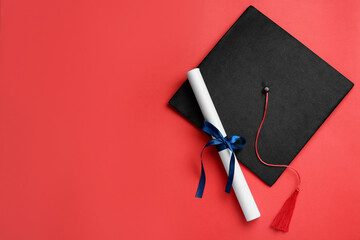 Graduation hat and diploma on red background, flat lay. Space for text