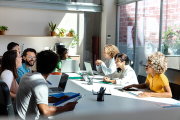 Group of multiracial young colleagues talking in big bright office space. Copy space.