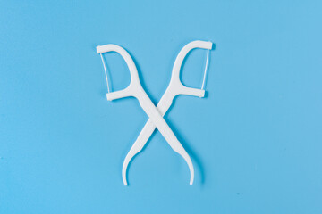 Plastic white dental toothpick with dental floss on blue background.