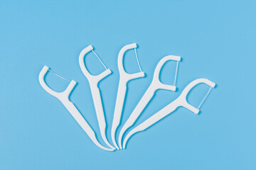 Plastic white dental toothpick with dental floss on blue background.