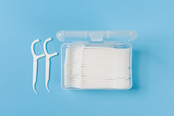 white dental toothpick with dental floss in box on blue background.