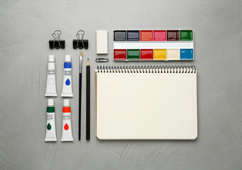 Flat lay composition with blank sketchbook on light grey stone table. Space for text