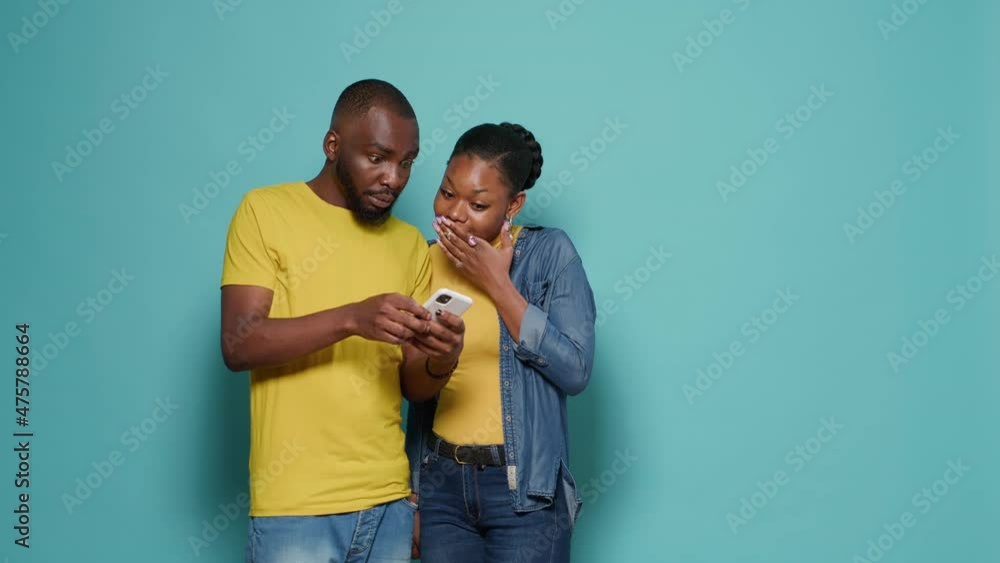 Poster man and woman using internet on smartphone together in front of camera. people looking at mobile pho