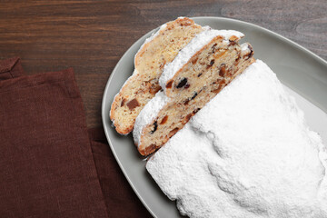 Traditional Christmas Stollen with icing sugar on wooden table, flat lay