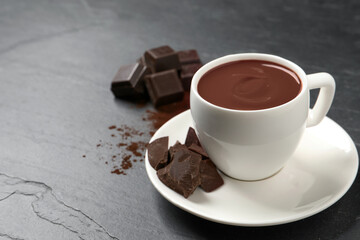 Yummy hot chocolate in cup on dark table, space for text