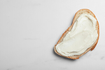 Slice of bread with tasty cream cheese on white marble table, top view. Space for text