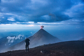 Climber on Acatenango watching Fuego volcano erupting, Antigua, Guatemala