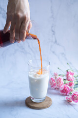 Iced black tea with milk. Thai ice tea with milk on wood disk in marble background.