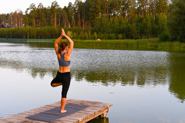 Fototapeta na wymiar A woman is engaged in physiotherapy exercises on the lake in nature. The concept of treating diseases.